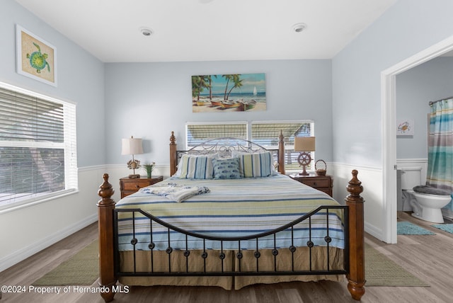 bedroom with hardwood / wood-style floors, ensuite bath, and multiple windows