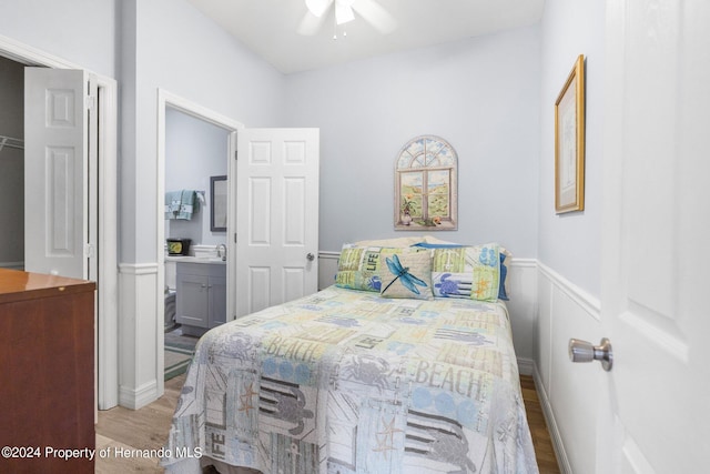 bedroom with ensuite bathroom, light hardwood / wood-style flooring, ceiling fan, and sink