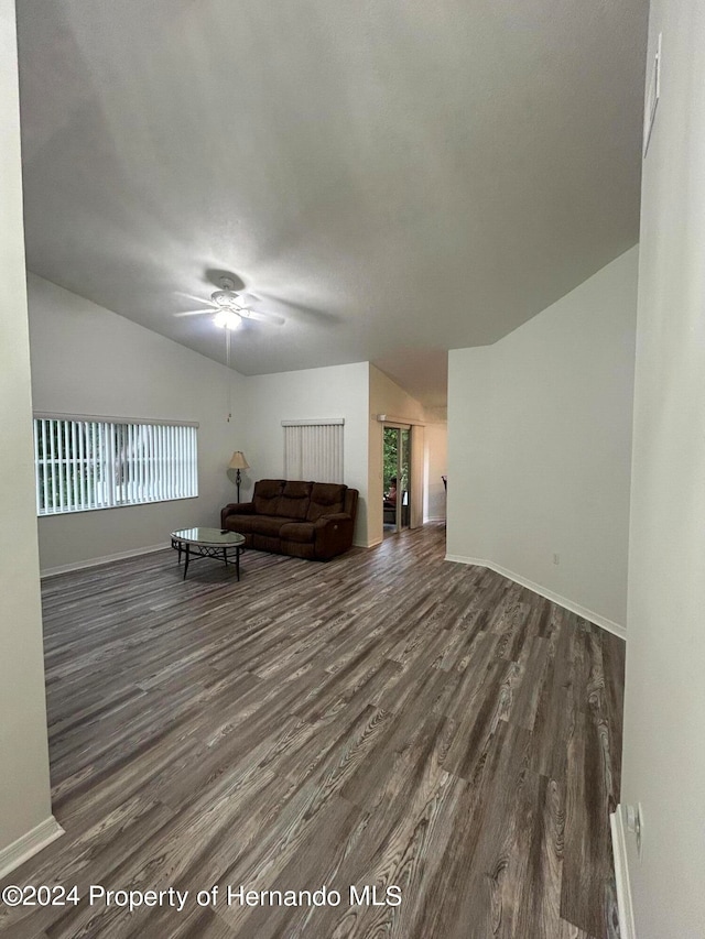 living room featuring dark hardwood / wood-style flooring, vaulted ceiling, and ceiling fan