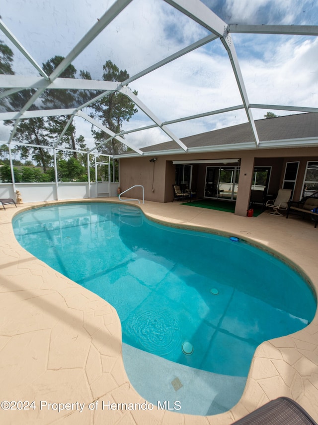 view of pool featuring glass enclosure and a patio area