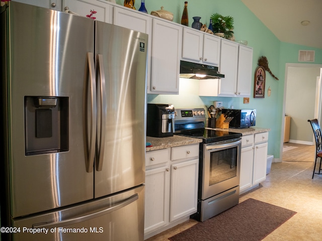 kitchen with appliances with stainless steel finishes, vaulted ceiling, white cabinetry, and light stone counters