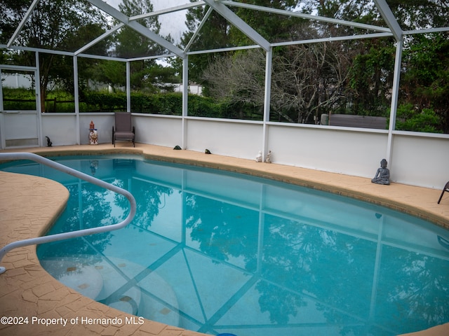 view of swimming pool featuring a lanai