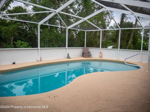 view of swimming pool with a patio area and a lanai