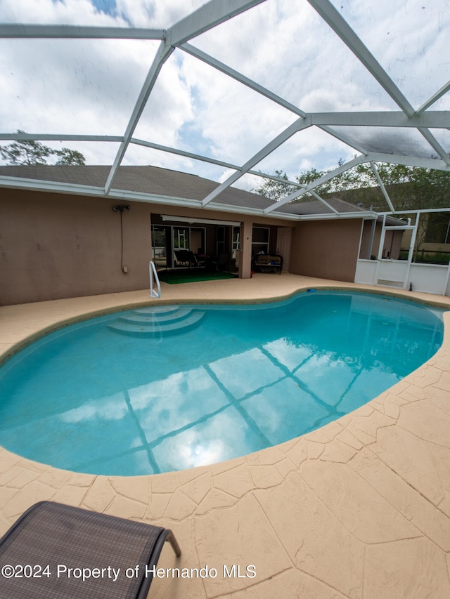 view of swimming pool with a patio area and a lanai