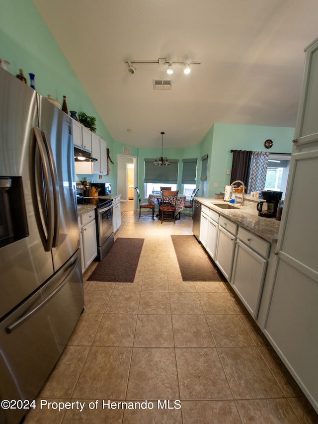 kitchen featuring light stone countertops, appliances with stainless steel finishes, decorative light fixtures, and plenty of natural light