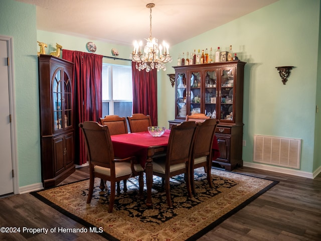 dining space featuring dark hardwood / wood-style flooring, lofted ceiling, and a chandelier