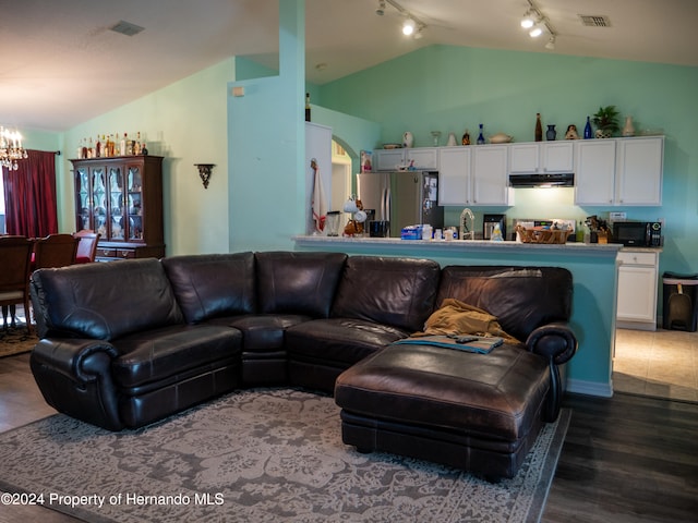 living room featuring lofted ceiling, dark wood-type flooring, an inviting chandelier, track lighting, and sink