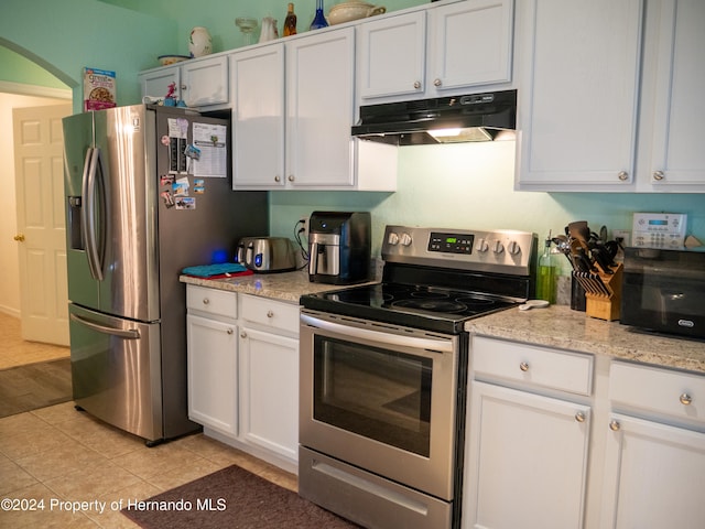 kitchen with white cabinets, appliances with stainless steel finishes, light stone counters, and light tile patterned flooring