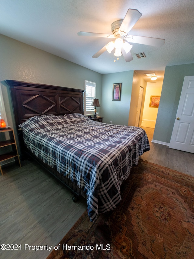 bedroom with ensuite bath, ceiling fan, dark hardwood / wood-style flooring, and a textured ceiling