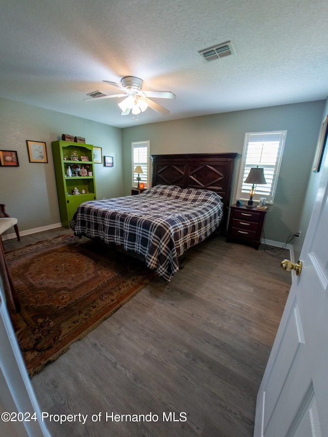 bedroom featuring ceiling fan, dark hardwood / wood-style flooring, and a textured ceiling