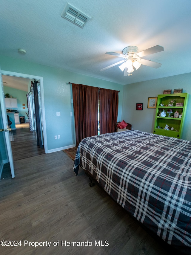 bedroom with ceiling fan, dark hardwood / wood-style flooring, and a textured ceiling