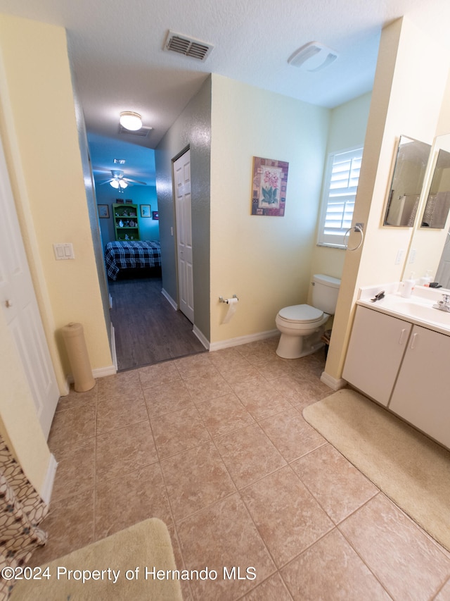 bathroom with ceiling fan, tile patterned flooring, a textured ceiling, toilet, and vanity