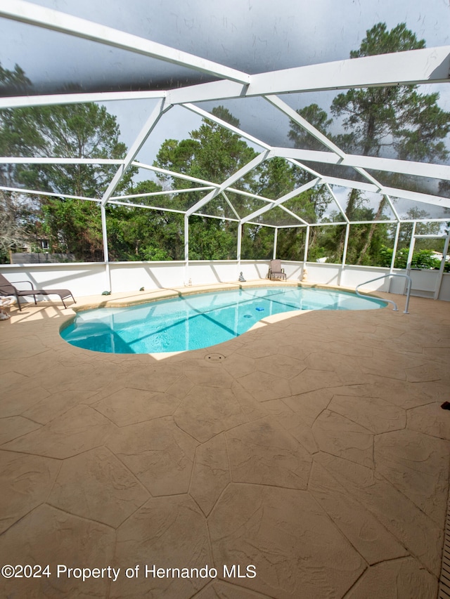 view of swimming pool featuring a patio and glass enclosure