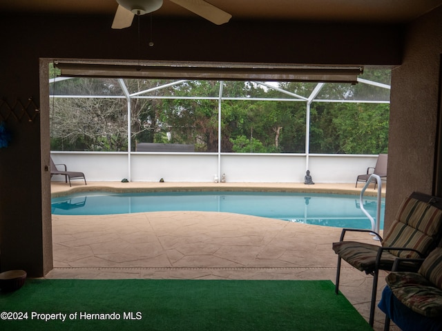 view of pool with glass enclosure, ceiling fan, and a patio area