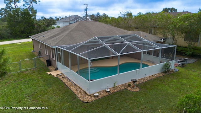 view of swimming pool featuring a lawn and a lanai