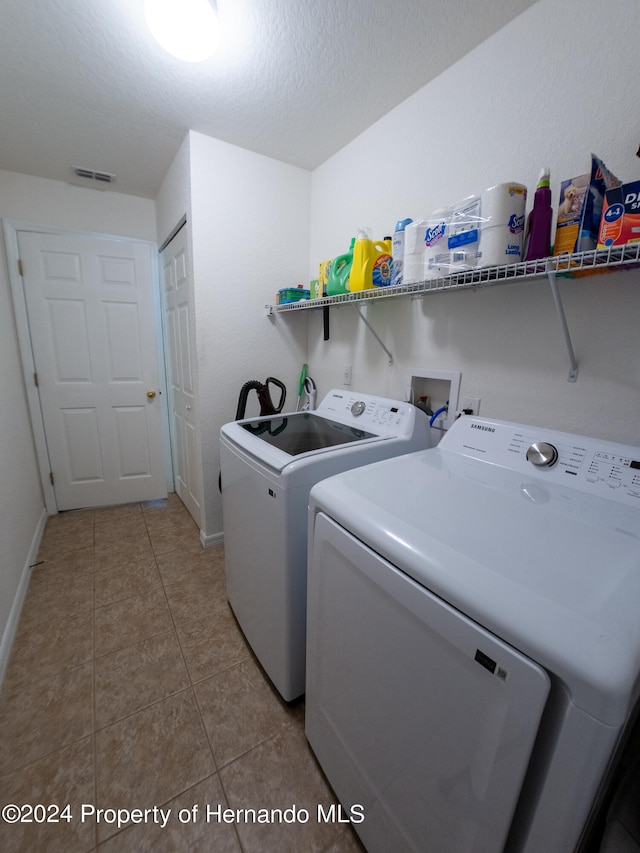 washroom with washing machine and dryer, light tile patterned floors, and a textured ceiling