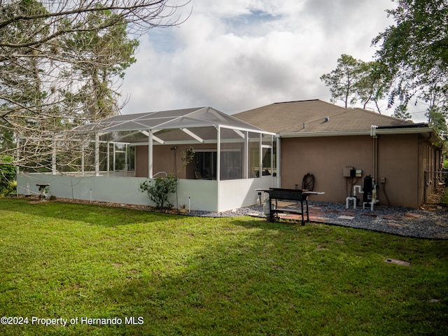 rear view of property with glass enclosure and a lawn