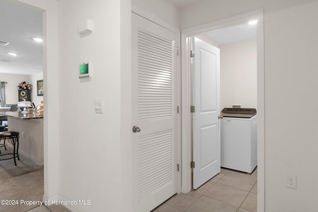 corridor with light tile patterned floors and washer / dryer