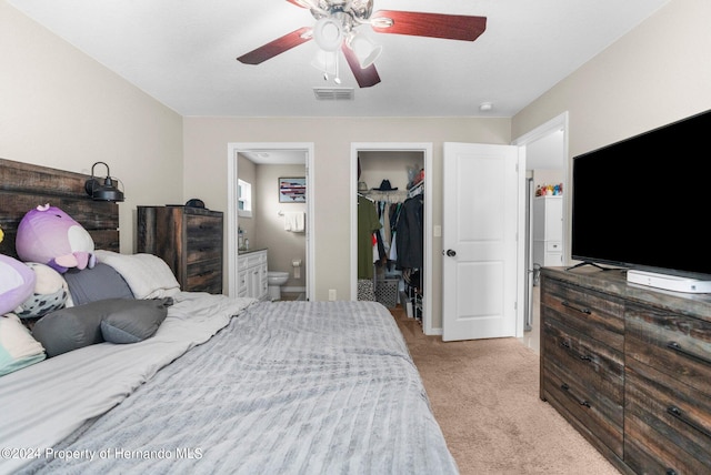 bedroom featuring a closet, a spacious closet, light carpet, ceiling fan, and ensuite bathroom