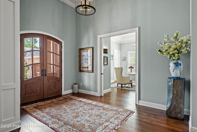 entrance foyer with ornamental molding, a chandelier, french doors, and dark hardwood / wood-style floors