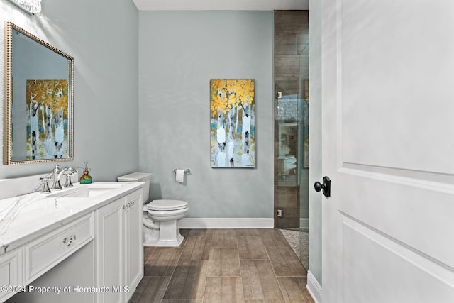 bathroom featuring hardwood / wood-style flooring, a shower with door, vanity, and toilet