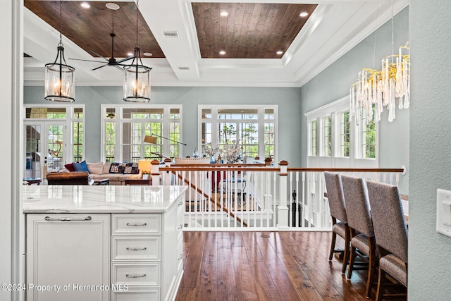 kitchen with french doors, light stone counters, white cabinetry, decorative light fixtures, and dark hardwood / wood-style flooring