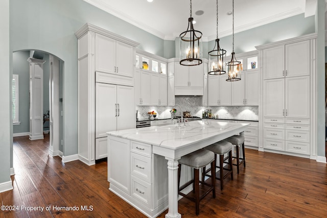 kitchen featuring white cabinetry, light stone counters, dark hardwood / wood-style floors, and a kitchen island with sink