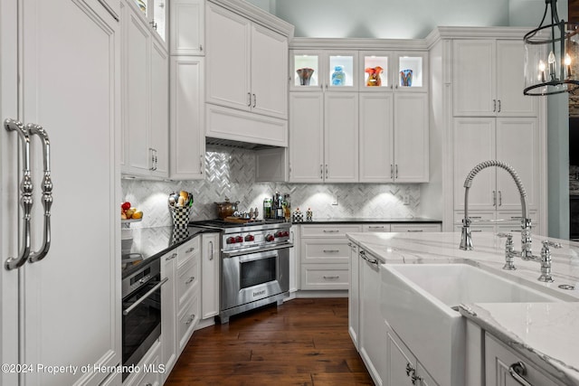 kitchen featuring stainless steel appliances, dark hardwood / wood-style floors, white cabinetry, and dark stone countertops