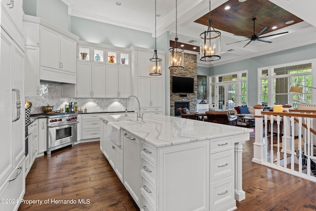 kitchen featuring designer stove, a stone fireplace, white cabinetry, dark hardwood / wood-style floors, and sink