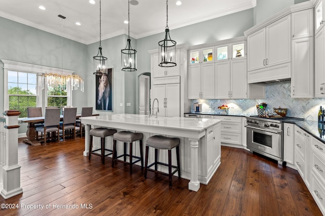 kitchen with a center island with sink, white cabinetry, dark hardwood / wood-style floors, pendant lighting, and high quality appliances