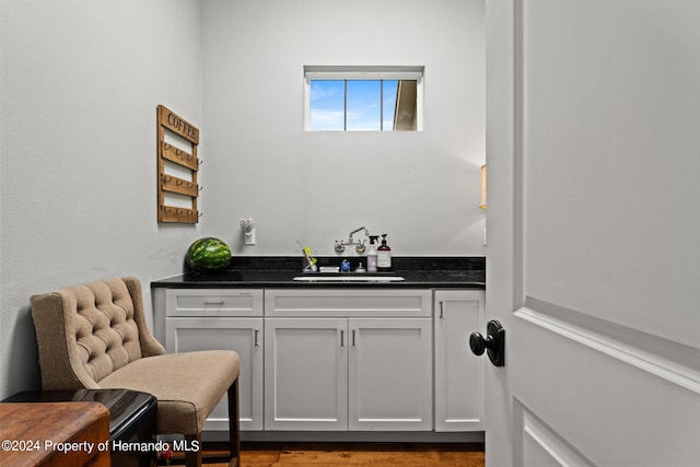 bar featuring sink, light hardwood / wood-style floors, and white cabinets