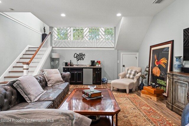 living room featuring bar area, lofted ceiling, and wood-type flooring