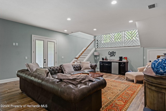 living room featuring a wealth of natural light, wood-type flooring, indoor bar, and french doors