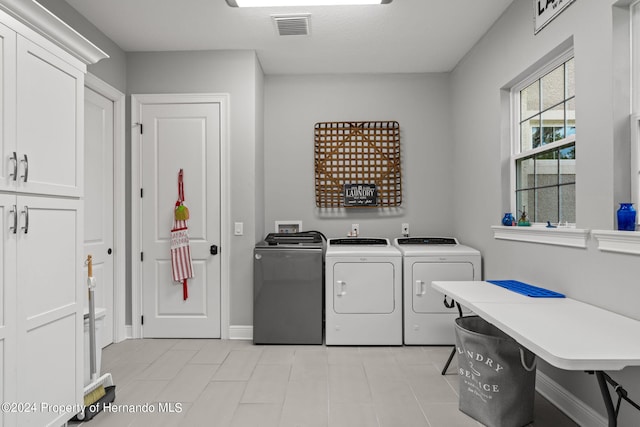 washroom with cabinets, independent washer and dryer, and light tile patterned floors