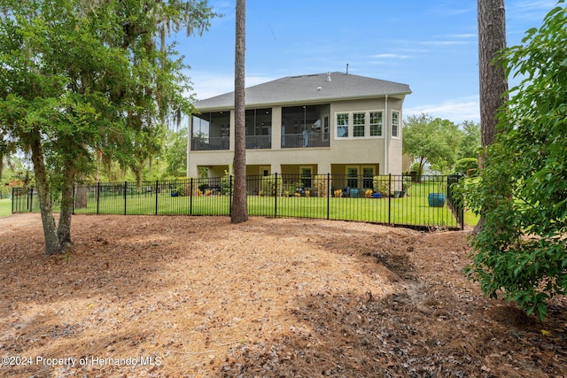 back of house with a sunroom and a lawn