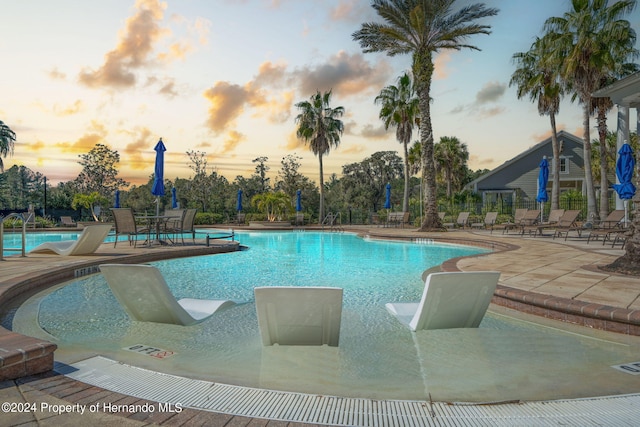 pool at dusk featuring a patio area