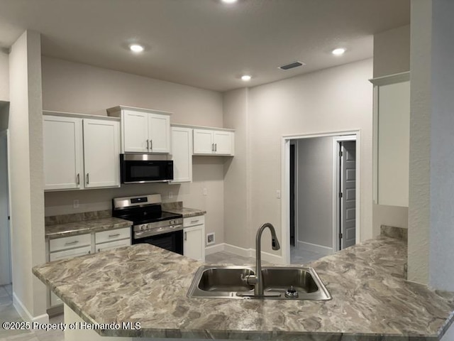 kitchen with kitchen peninsula, sink, white cabinetry, stainless steel electric range oven, and light stone countertops