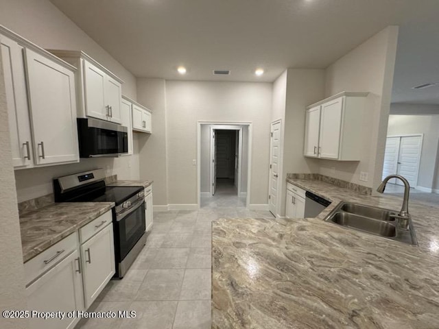 kitchen featuring light stone countertops, stainless steel appliances, white cabinets, and sink