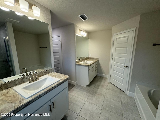 bathroom with vanity, tile patterned flooring, a textured ceiling, and a bath