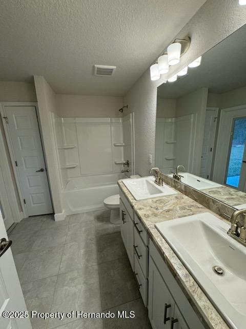 full bathroom with tub / shower combination, a textured ceiling, toilet, and vanity