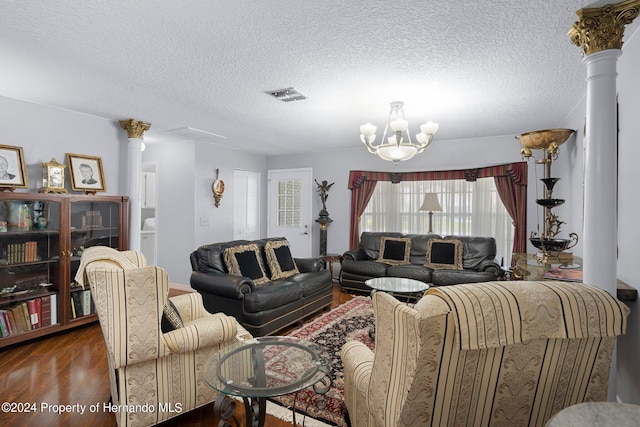 living room featuring dark hardwood / wood-style flooring, a textured ceiling, decorative columns, and an inviting chandelier