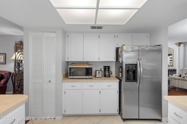 kitchen with stainless steel appliances, white cabinets, and light tile patterned floors