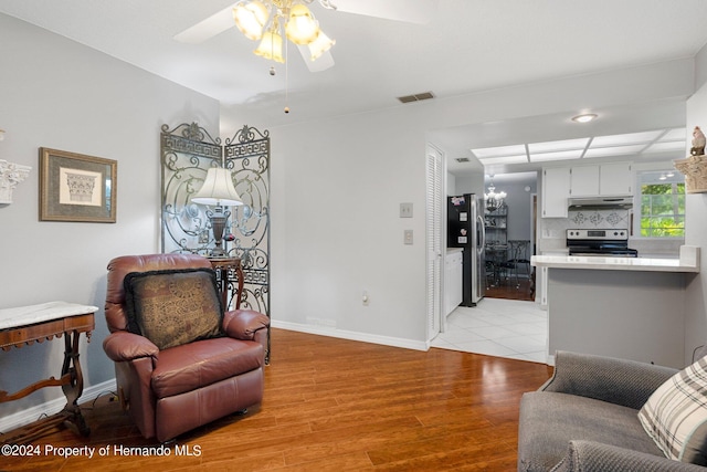 living area with light wood-type flooring and ceiling fan