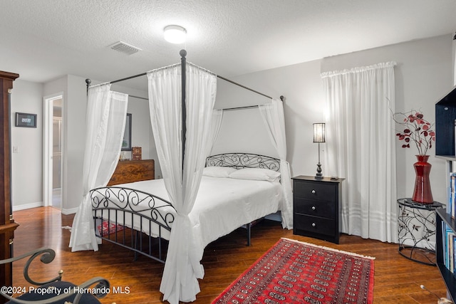 bedroom featuring a textured ceiling and dark hardwood / wood-style floors