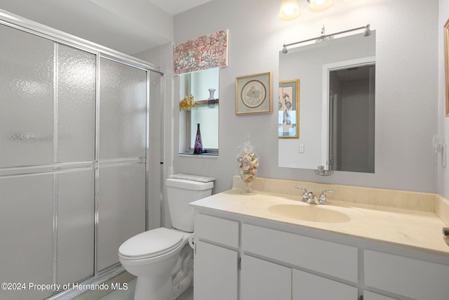 bathroom featuring a shower with door, vanity, and toilet