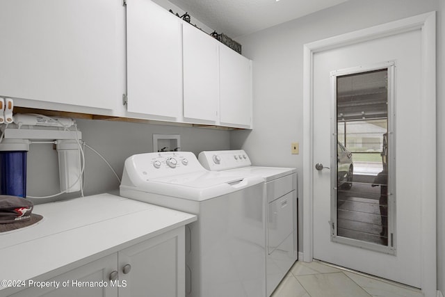 clothes washing area featuring a textured ceiling, cabinets, and washer and dryer