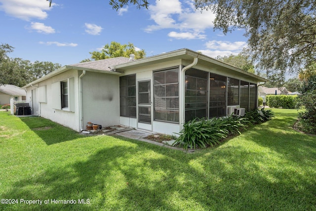 back of property with a lawn and a sunroom