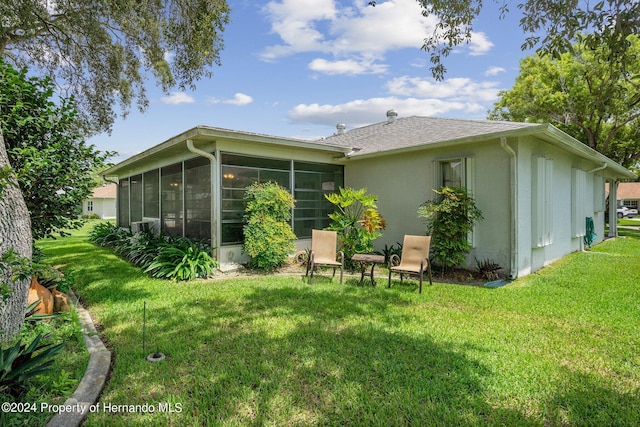 back of house with a sunroom and a lawn