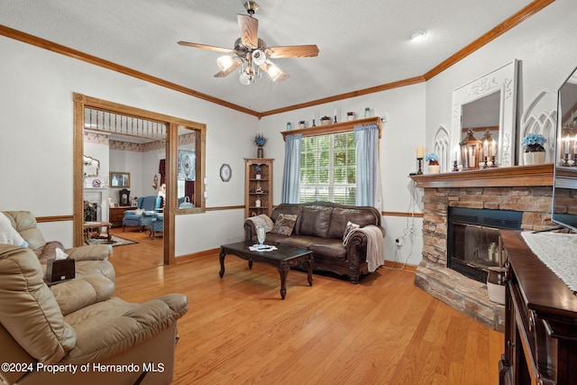 living room with light hardwood / wood-style floors, a textured ceiling, ornamental molding, ceiling fan, and a fireplace