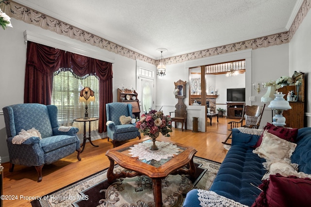 living room featuring hardwood / wood-style floors, a notable chandelier, ornamental molding, and a textured ceiling